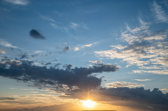 Beautiful Blue Sunset Sky with Bright Sun Glow and Dark Clouds.
