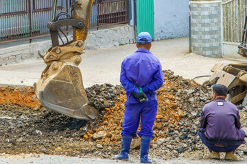 Construction workers observing digger on urban street © IbragimovN