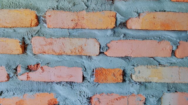 Unfinished red brick wall texture with rough grey cement mortar, background for construction and architecture industry.