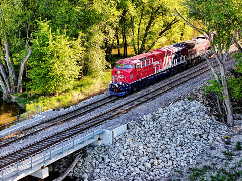 Savanna, Illinois May 10, 2026 CPKC 776 America 250 locomotive pulling  freight on parallel tracks through a lush green forest