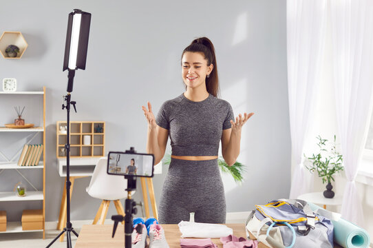 Female vlogger, healthy sport blogger happily looking in camera recording video for popular blog. Social media influencer in sportswear reviewing, marketing fitness goods for healthy lifestyle online