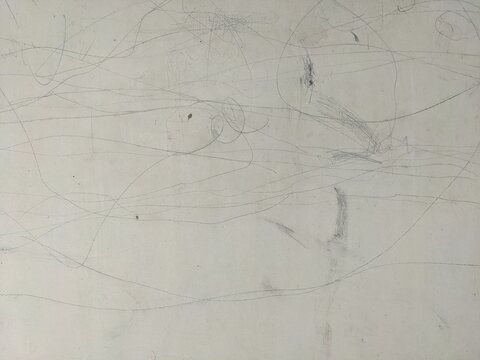 Abstract background of messy pencil scribbles and graphite smudge marks on a dusty white wall texture with thin random curved lines concept