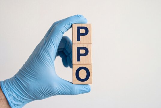 A close-up view of a hand wearing a blue medical glove holding a stack of wooden blocks that spell out PPO against a plain white background.