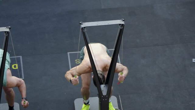 Male athlete powers through a SkiErg station during an intense HYROX fitness race showcasing cardiovascular endurance upper body strength speed and athletic conditioning
