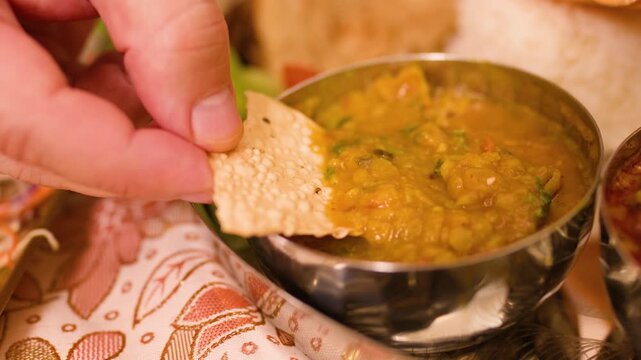 Hand Dipping Papadum into Indian Dal Lentil Stew