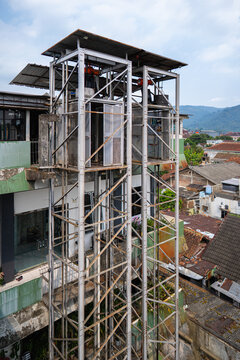 Outdoor cargo elevator structure on an old urban building background, industrial lift with steel frame construction, hoist mechanisms for vertical transport goods or construction materials