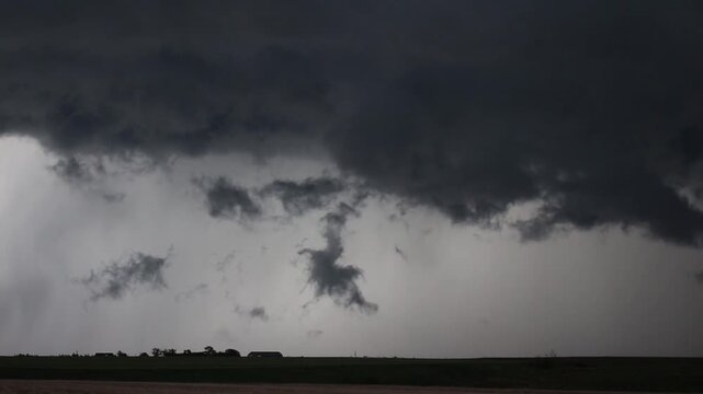 Menacing scud clouds churn underneath  the base of a dark storm cloud. Time lapse.