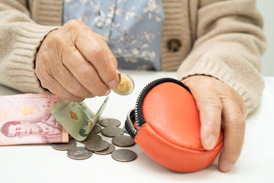 Asian senior or elderly old lady woman holding counting coin money in purse. Poverty, saving problem in retirement.