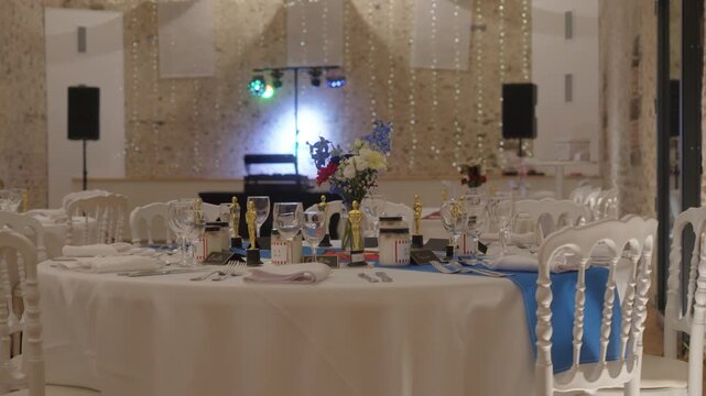 Orbiting View of Wedding Reception Hall Table Decorated with Oscar Statuettes, Floral Centerpieces, and DJ Lights