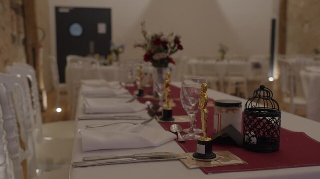 Low-Angle Shallow Focus Tracking Shot of Decorated Wedding Banquet Table with Oscar Statuettes