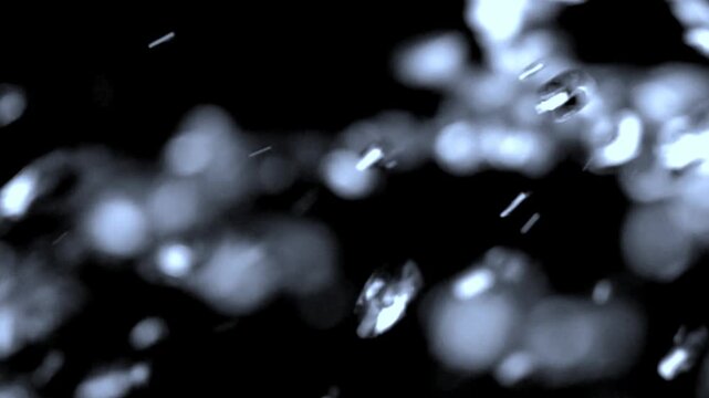 Water droplets splash across a black surface in dramatic slow motion.