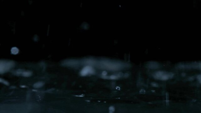 Realistic water stream creates dynamic droplets and splashes on black.