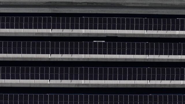 Rooftop photovoltaic arrays, revealing parallel solar panel rows, geometric rooftop patterns and renewable electricity generation, top-down drone forward flyover