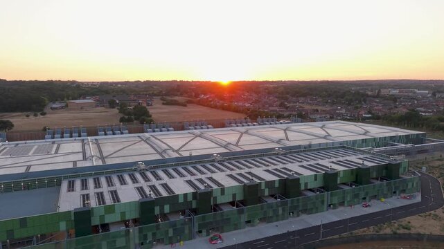 Google data centre drone descent in Waltham Cross at sunset as the sun drops below the horizon, revealing the roofline, front facade, surrounding fields and houses behind at golden hour.