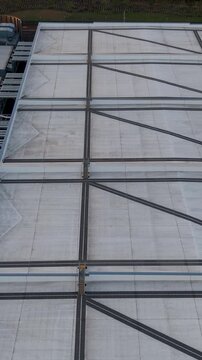 Google data centre Waltham Cross, Hertfordshire rightward pan from rear to front showing roof structure, cooling units, pipework, service corridors and perimeter fencing in the UK. Vertical format.