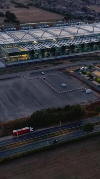 Google data centre Waltham Cross hyperlapse pan after sunset over Hertfordshire, UK. Aerial view of campus buildings, service roads, nearby motorway traffic and surrounding fields. Vertical format.