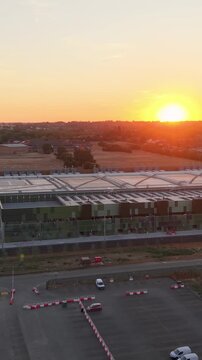 Google data centre flyover at sunset in Waltham Cross, Hertfordshire, UK. Drone advances over vast industrial campus near fields, highlighting land use, energy demand, and environment impact. Vertical