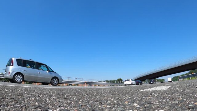Vehicles traveling along A4 Autostrada near Cascina Merlata overpass in Milan Italy showing highway pavement guardrails and elevated roadway under clear blue sky