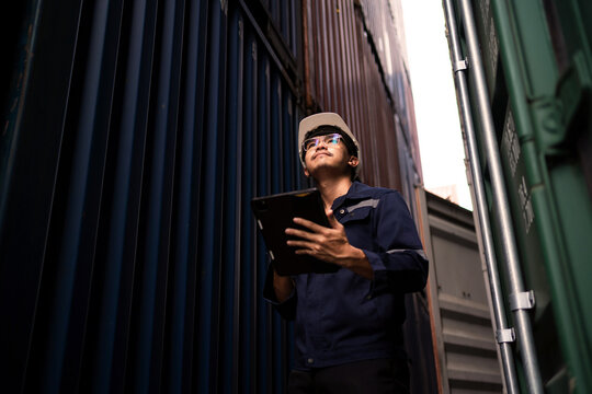 Logistics inspector with tablet checking cargo containers in narrow yard alley.  Smart Logistics, Cargo Verification, Narrow Yard Operations, Digital Stock Check