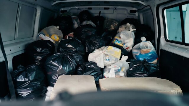 Interior of a delivery van filled with many garbage bags full of waste