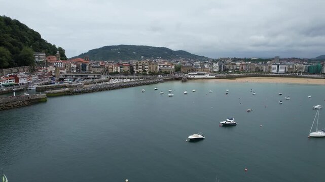 Aerial view of boats anchored in La Concha Bay with the city skyline and beach in the background in Donostia, Basque Country, Spain.