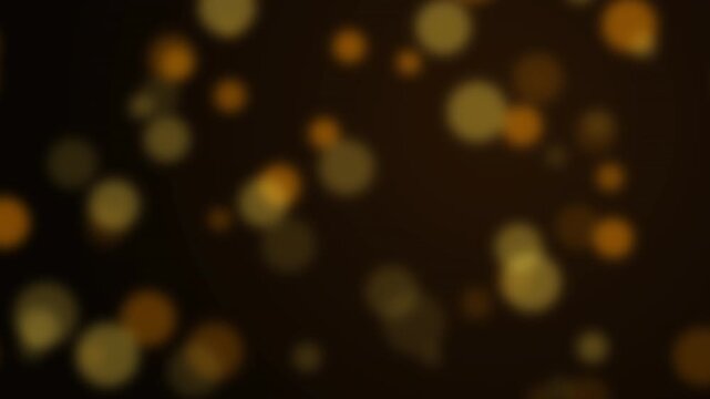 Abstract golden bokeh lights slowly floating against a black background