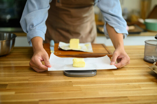 Cropped shot Man Measuring Butter on Kitchen Scale for Dessert Baking at Home