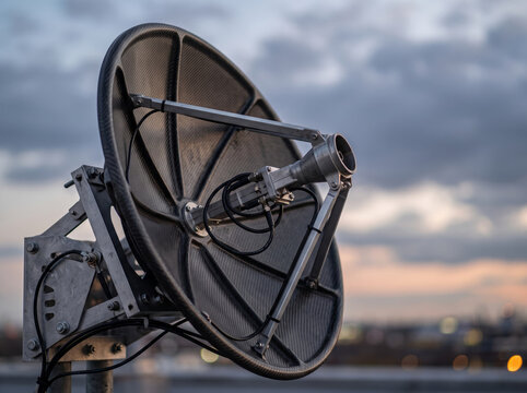 Large parabolic satellite dish antenna against evening twilight sky background
