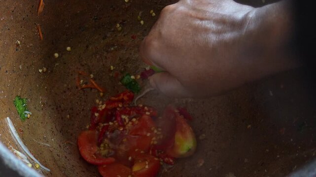 4K High angle close-up shot of red chilies and monosodium glutamate powder inside clay mortar for making Thai papaya salad, Cooking process Thai food spicy dish and street food.
