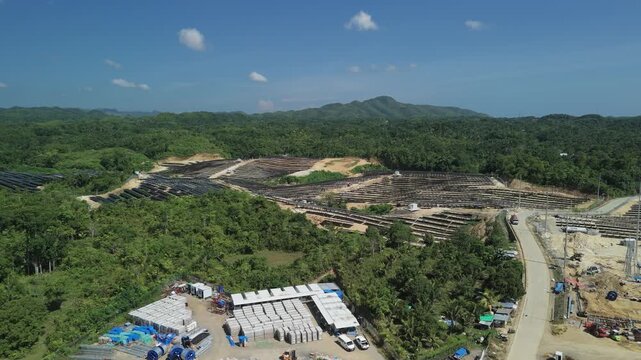 Aerial pull-back and ascending reveal of the Sikatuna Solar Power Plant surrounded by rolling hills and tropical forest in Bohol