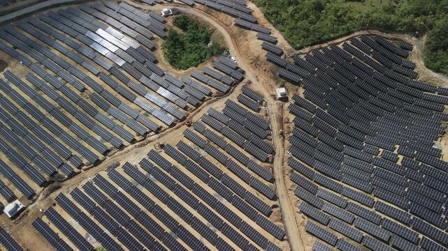 Drone ascends and pulls back over extensive solar panel arrays and access roads across the hillside Sikatuna solar plant in Bohol