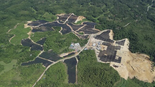 Drone approaches and flies over extensive solar panel arrays, access roads, and surrounding hills at the Sikatuna solar plant in Bohol