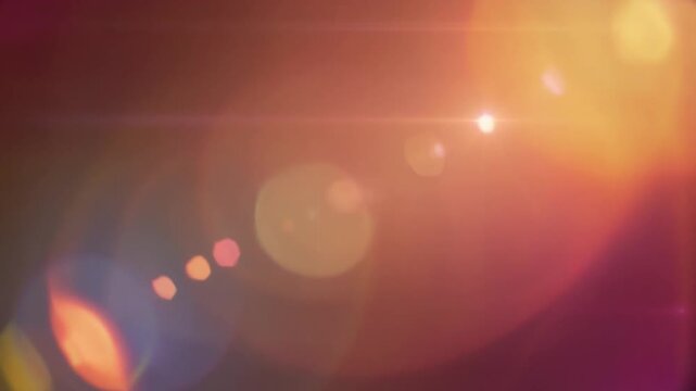 Soft glowing warm light leaks and bokeh particles drifting across a dark background. Seamless motion loop for cinematic and creative video projects.