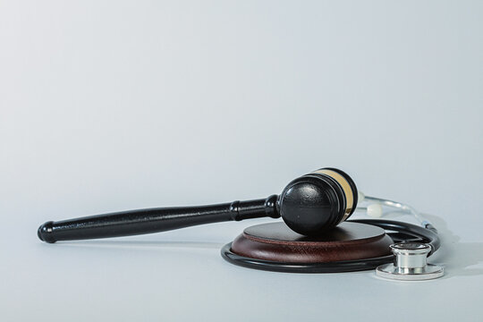 Solemn legal trial concept features wooden gavel and doctor stethoscope representing grave medical malpractice lawsuit and justice