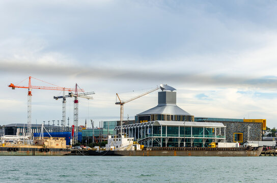 A modern waterfront building with a distinctive silver conical roof sits at the edge of Auckland Harbour