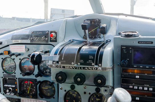 A detailed cockpit view inside a De Havilland aircraft in Auckland, New Zealand, showing throttle levers, analog gauges, and avionics across the instrument panel