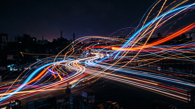 Long exposure light trails of city traffic on a highway at night, creating a dynamic sense of motion and speed
