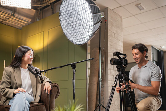 Content creator recording a female guest speaking into a microphone during a video podcast