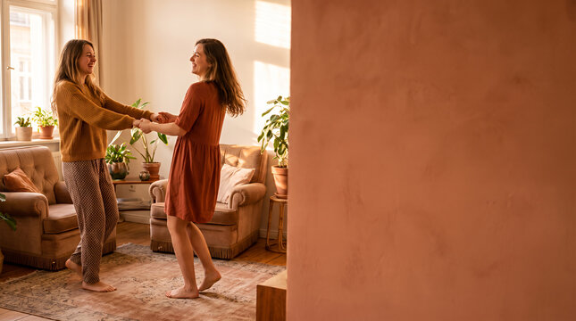 Two women holding hands in warm modern living room