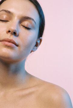 Young woman with closed eyes enjoying peaceful meditation moment in studio light