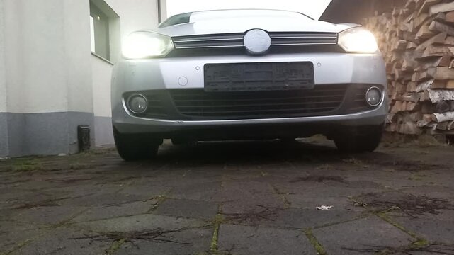 Revving engine with dynamic RPM sounds in low-angle view of car against rustic backdrop