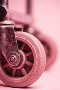 Close-up of a worn caster wheel on a pink background