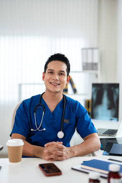 Happy successful doctor in medical office, looking at camera, smiling, posing for portrait. Confident male medical professional head shot.