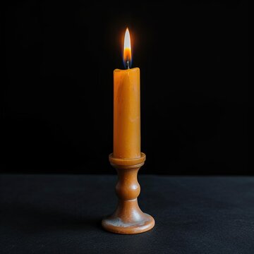 Burning beeswax candle in wooden holder