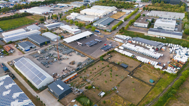 Aerial view of the industrial park in Trier Zewen featuring warehouses, logistics center with parked trucks, buses, and solar panels in Trier-Saarburg, Rhineland-Palatinate, Germany.