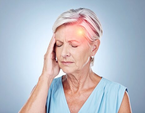 Senior woman suffering from acute sinus pain and migraine, pressing her fingers against her glowing temple.