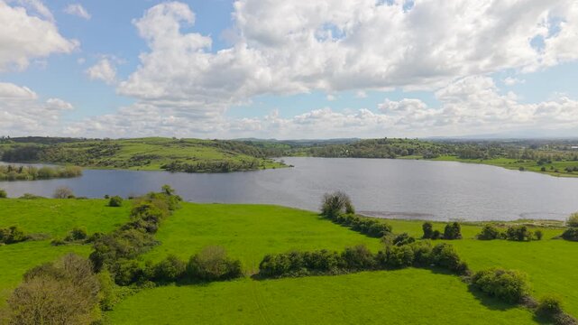 Wide aerial view of green fields and lake under partly cloudy sky in County Limerick