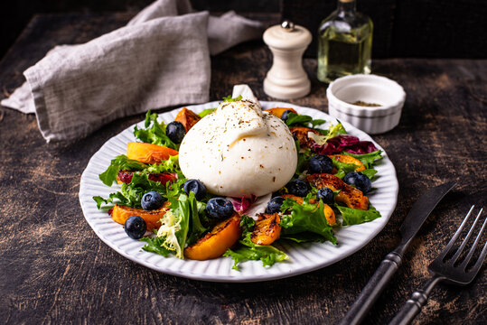 Delicious salad with burrata cheese grilled peaches and blueberry