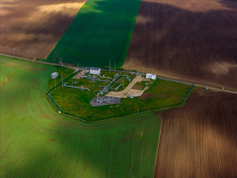 Aerial view of an industrial facility with pipelines and storage tanks surrounded by vast agricultural fields in the countryside in Mutenice, South Moravian Region, Czechia.