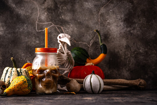 Halloween autumn drink pumpkin spicy latte in glass in shape of skull